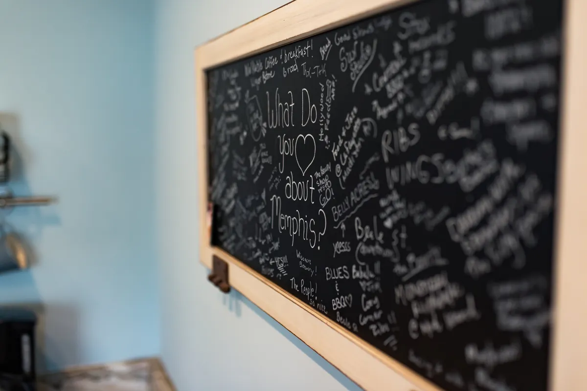This image features a chalkboard with handwritten notes and guest comments, framed in rustic wood. The communal element invites interaction, sharing experiences, and connecting creatively within the space.