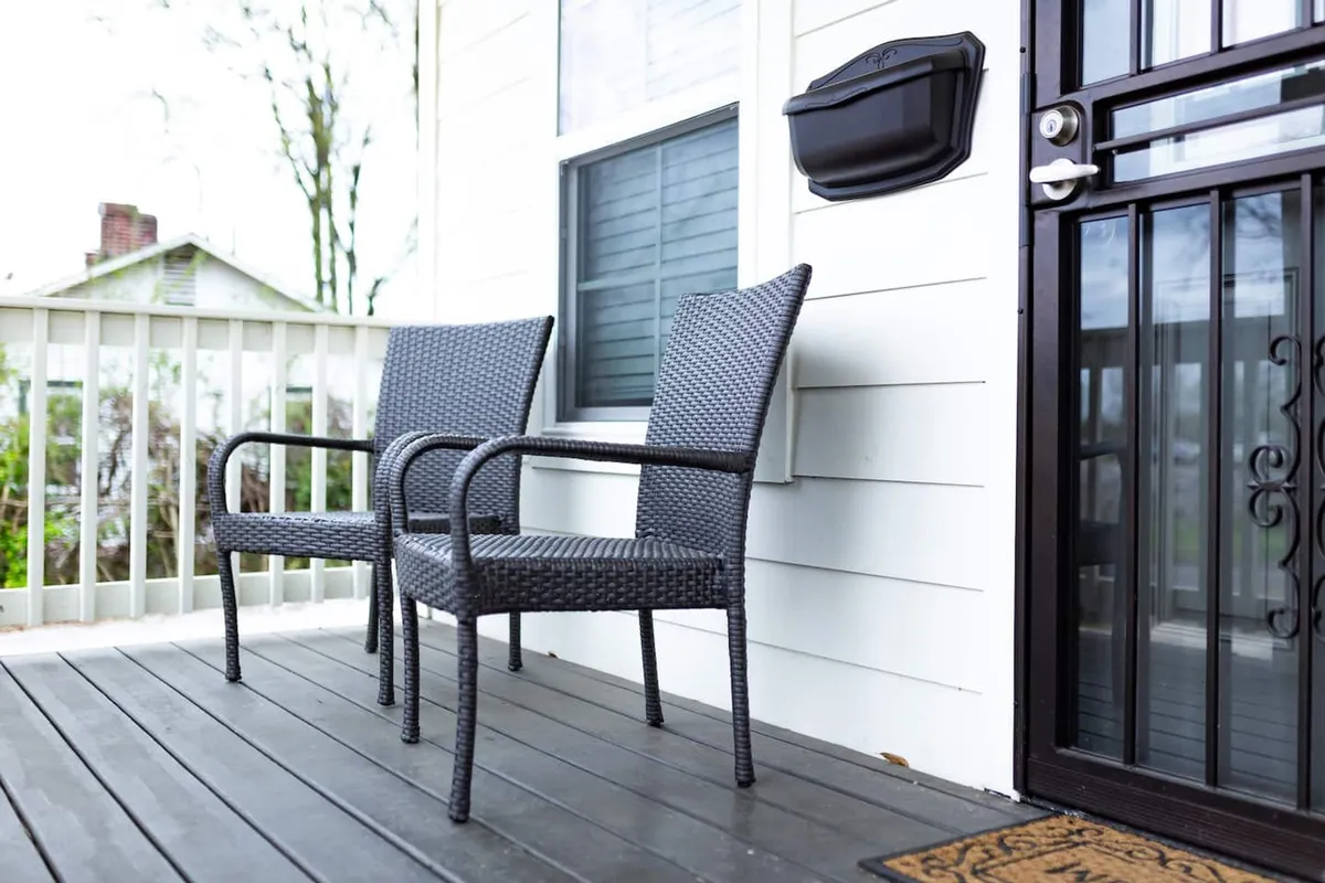 A close-up of two wicker chairs and a welcome mat by the front door, suggesting a cozy nook for conversation or quiet work. The warm, welcoming vibe is perfect for moments of connection or reflection, and the image focuses on the transition between private and shared spaces.
